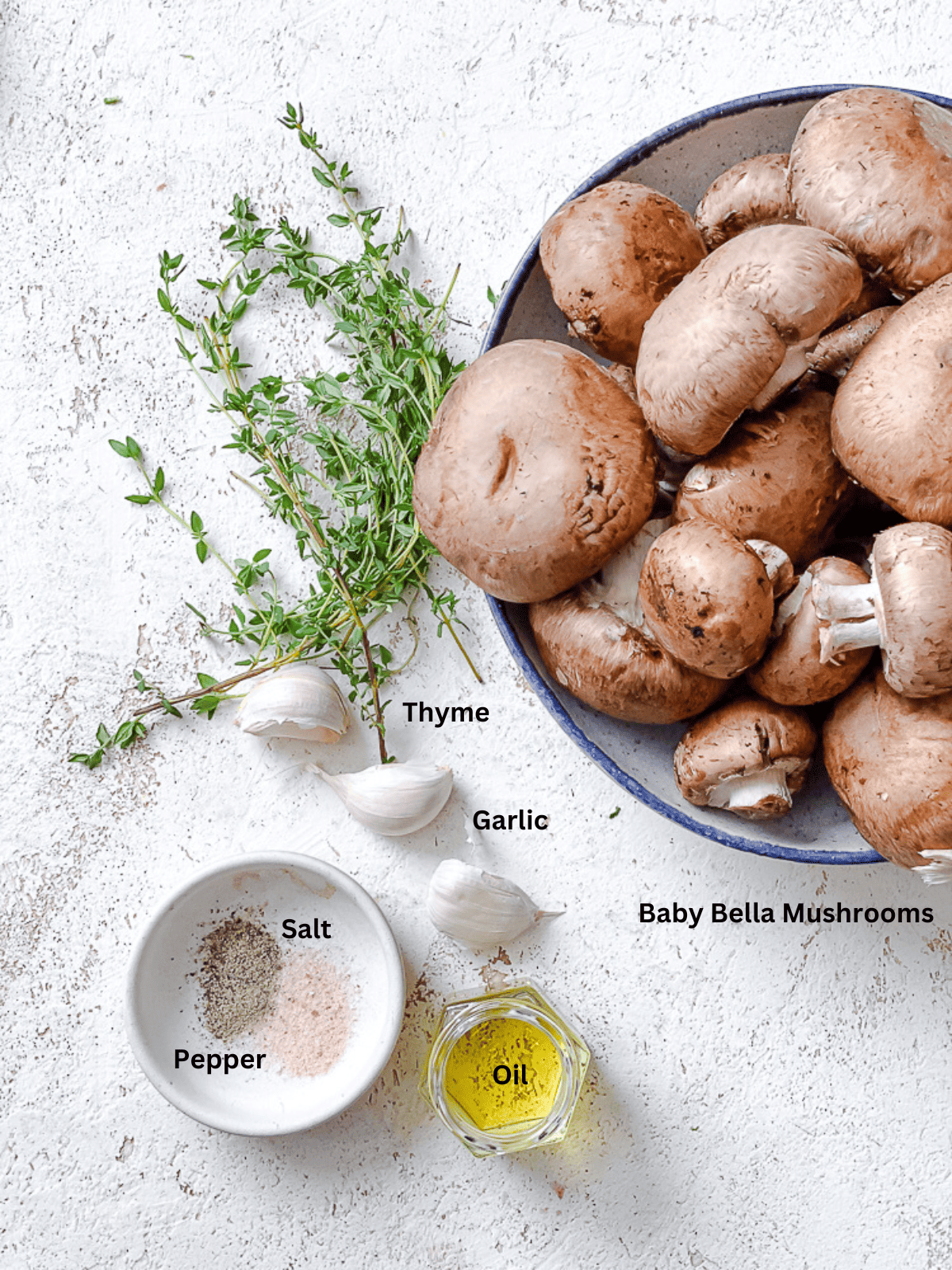 ingredients for Sauteed Mushrooms with Garlic and Thyme on a white surface