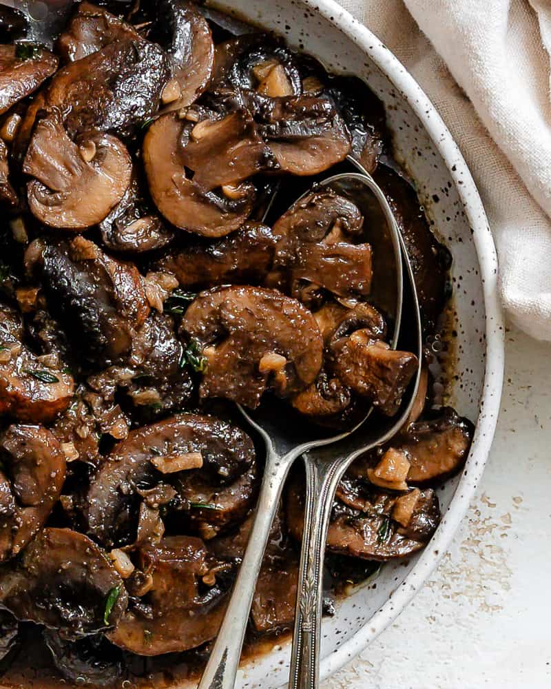 completed Sauteed Mushrooms with Garlic and Thyme on a white surface