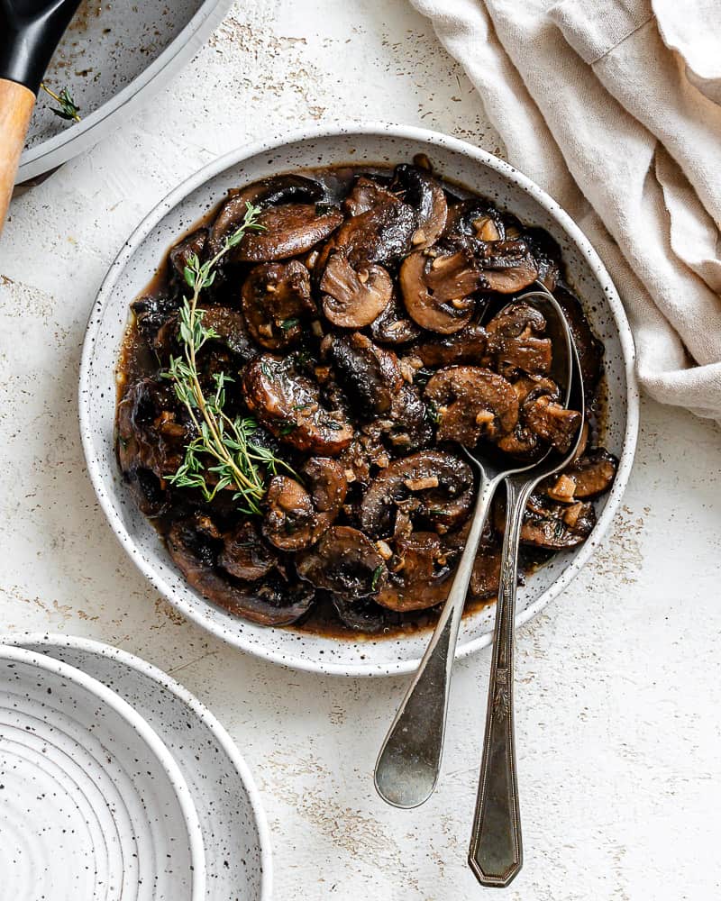 completed Sauteed Mushrooms with Garlic and Thyme on a white surface