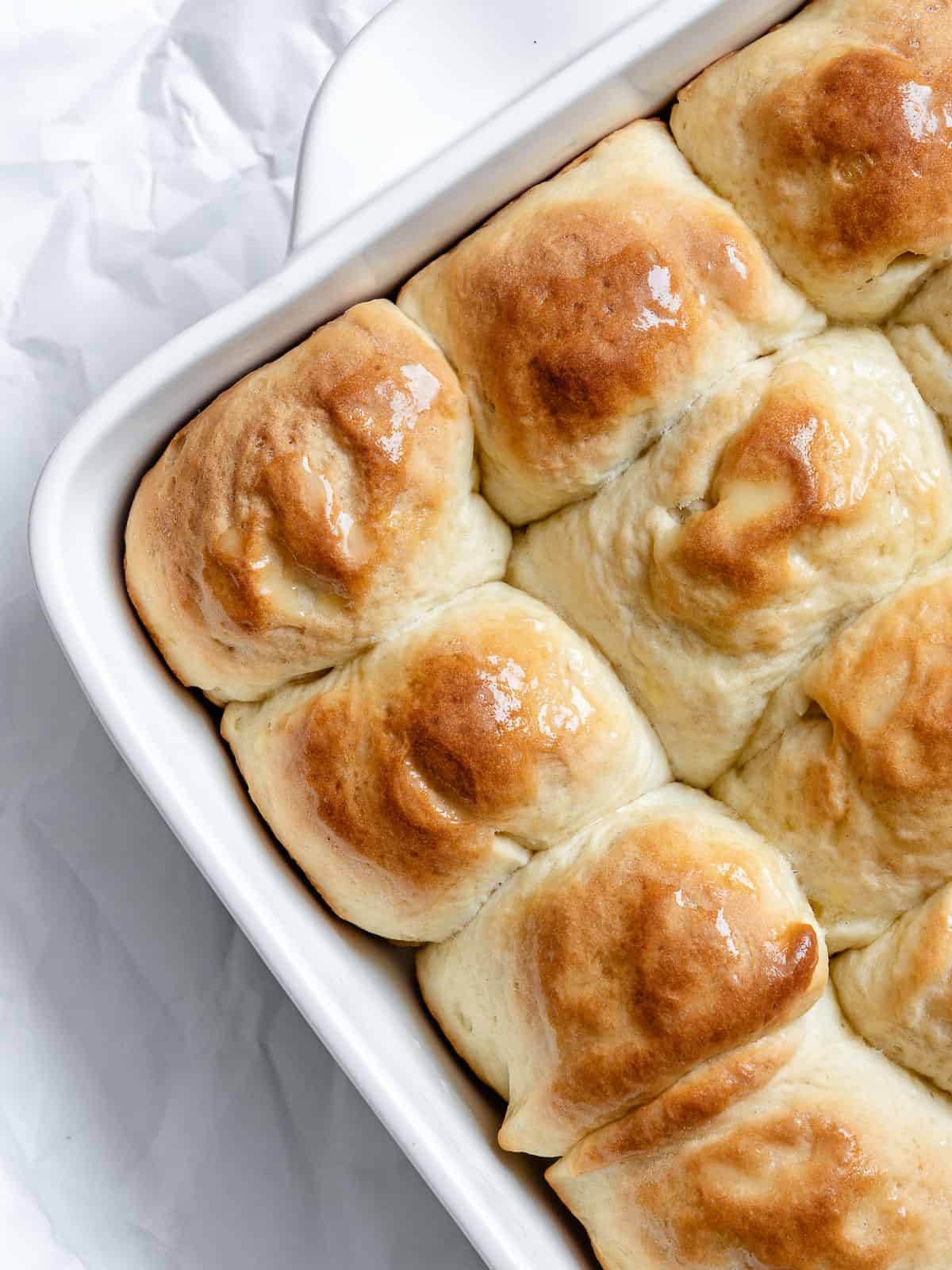 completed Easy Vegan Dinner Rolls on a white baking dish a،nst a white background