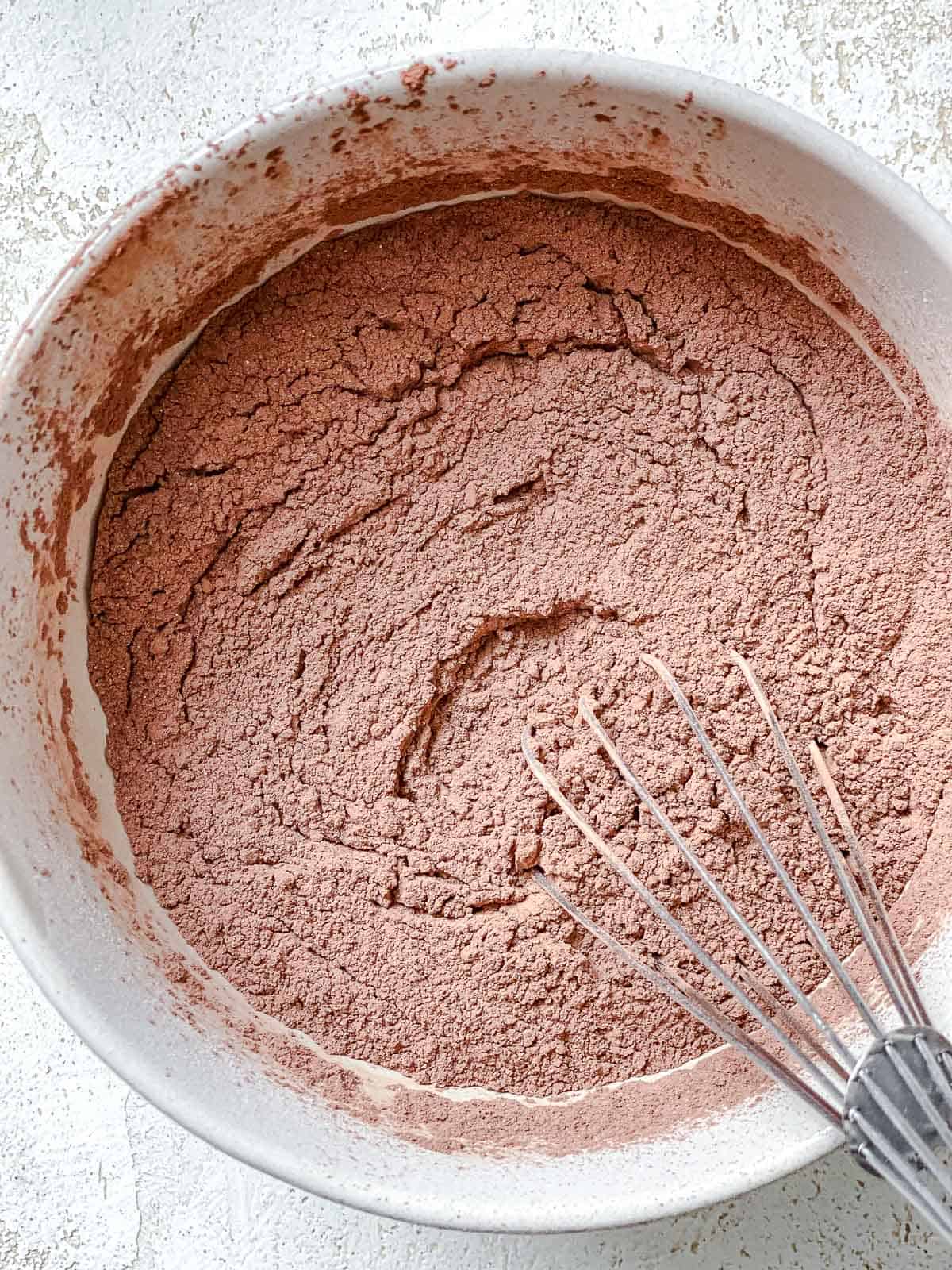 Cocoa powder and powdered sugar whisked together in a white bowl
