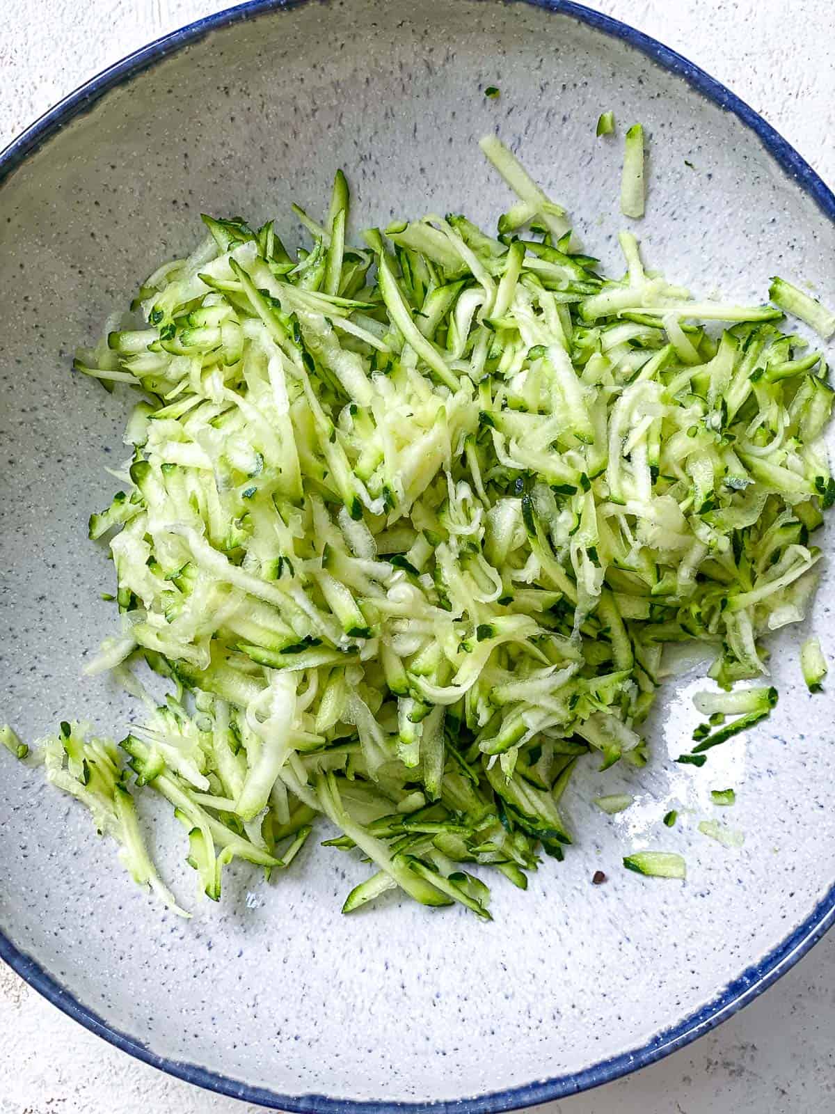 process shot showing grated zucchini in bowl