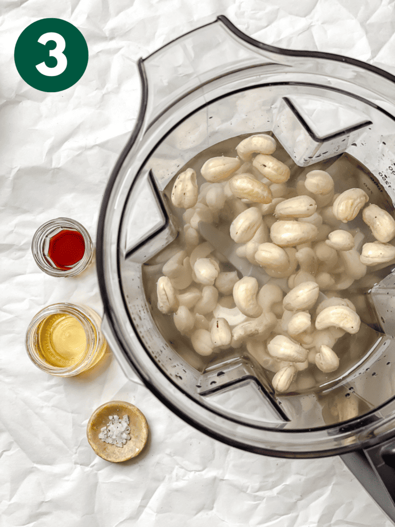 process shot showing cashews in blender alongside ingredients