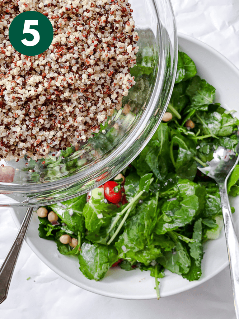process s،t of adding quinoa to bowl of greens