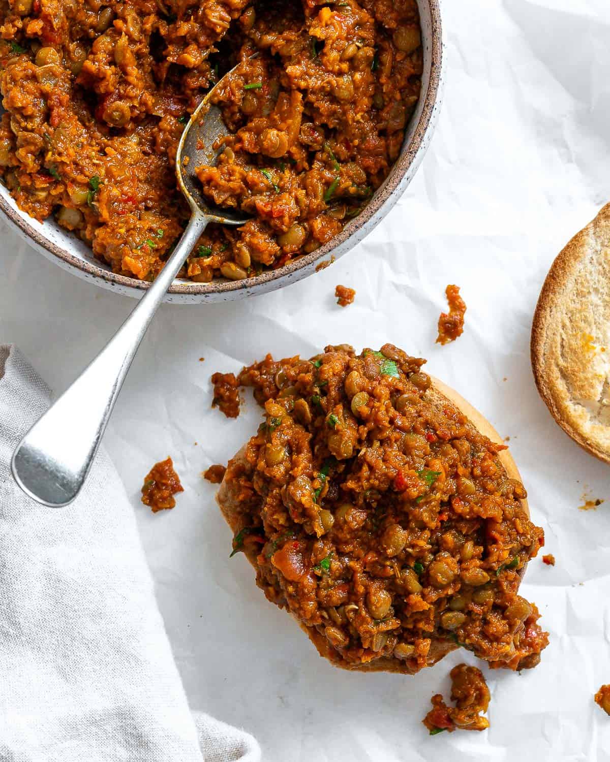completed Lentil Sloppy Joes (Stove or Slow Cooker) in a bowl and on a bun on a white surface