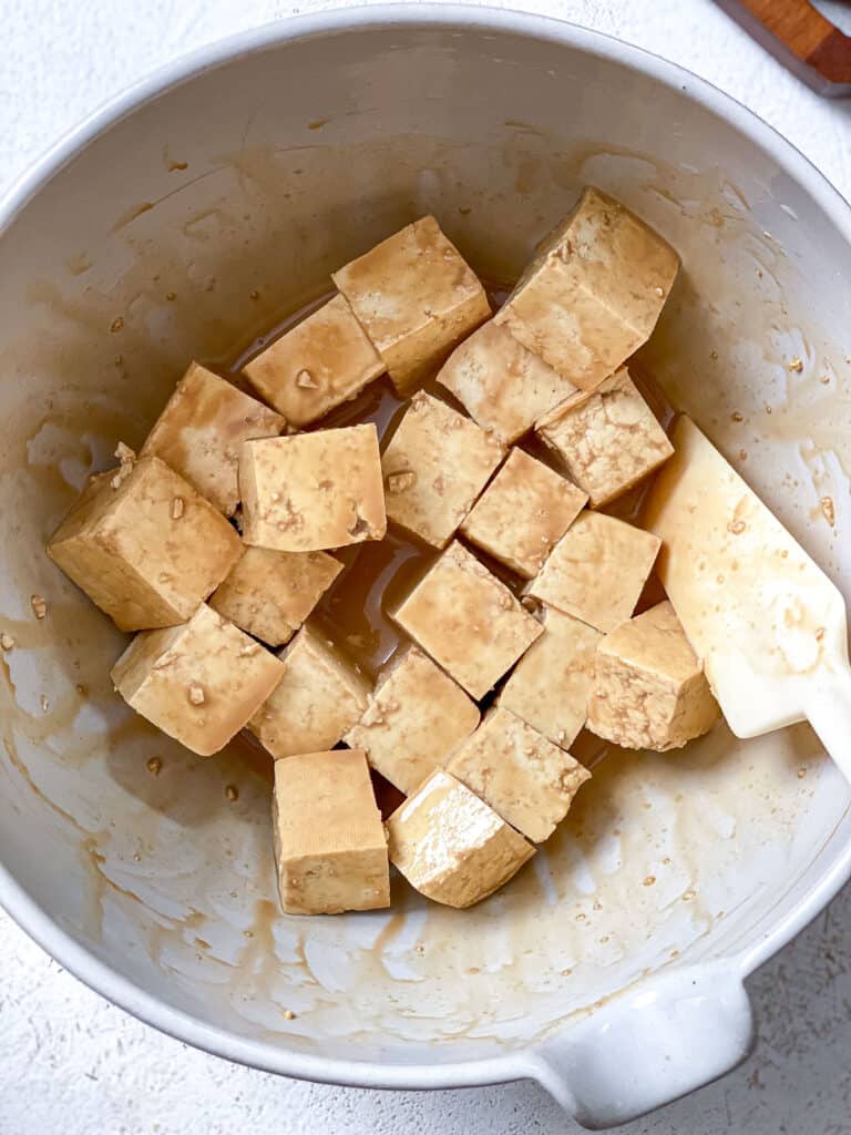 process shot of adding tofu to marinade in bowl