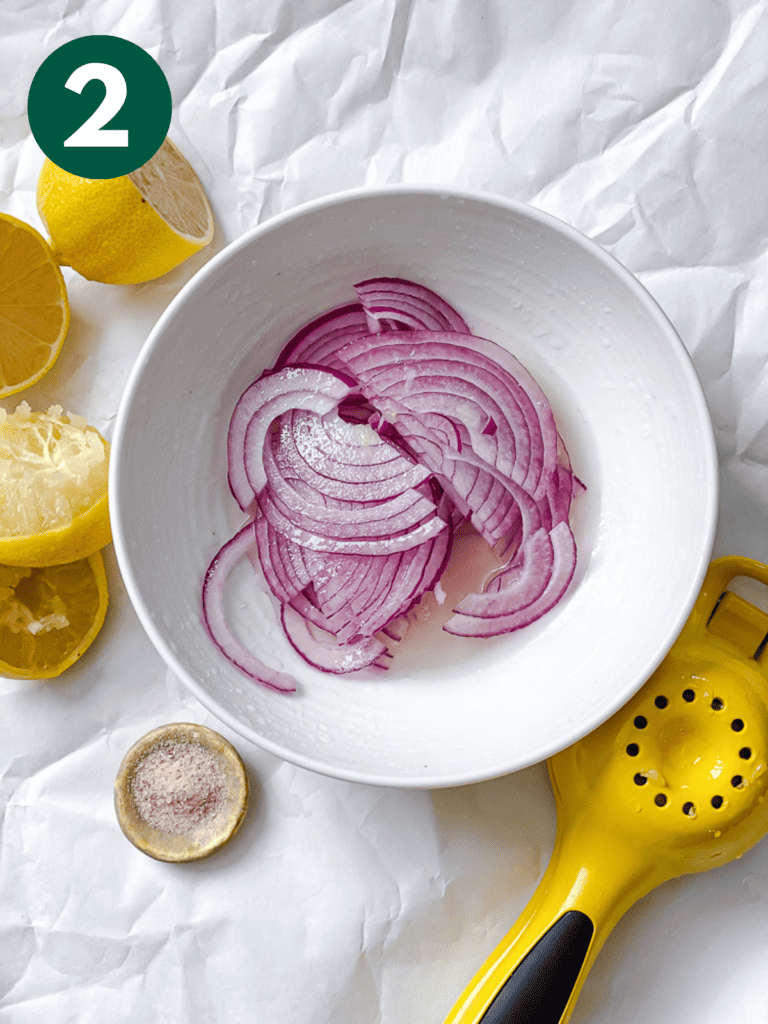 process shot showing sliced onions in a bowl with ingredients in the background