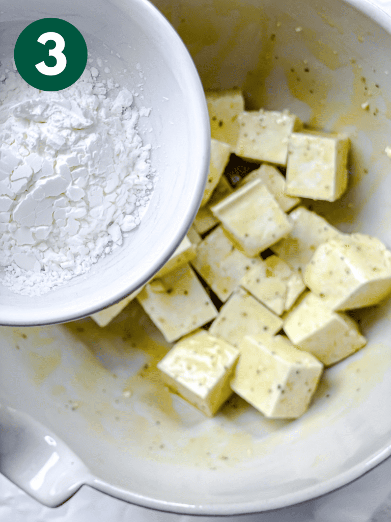 process shot showing cornstarch added to bowl of tofu