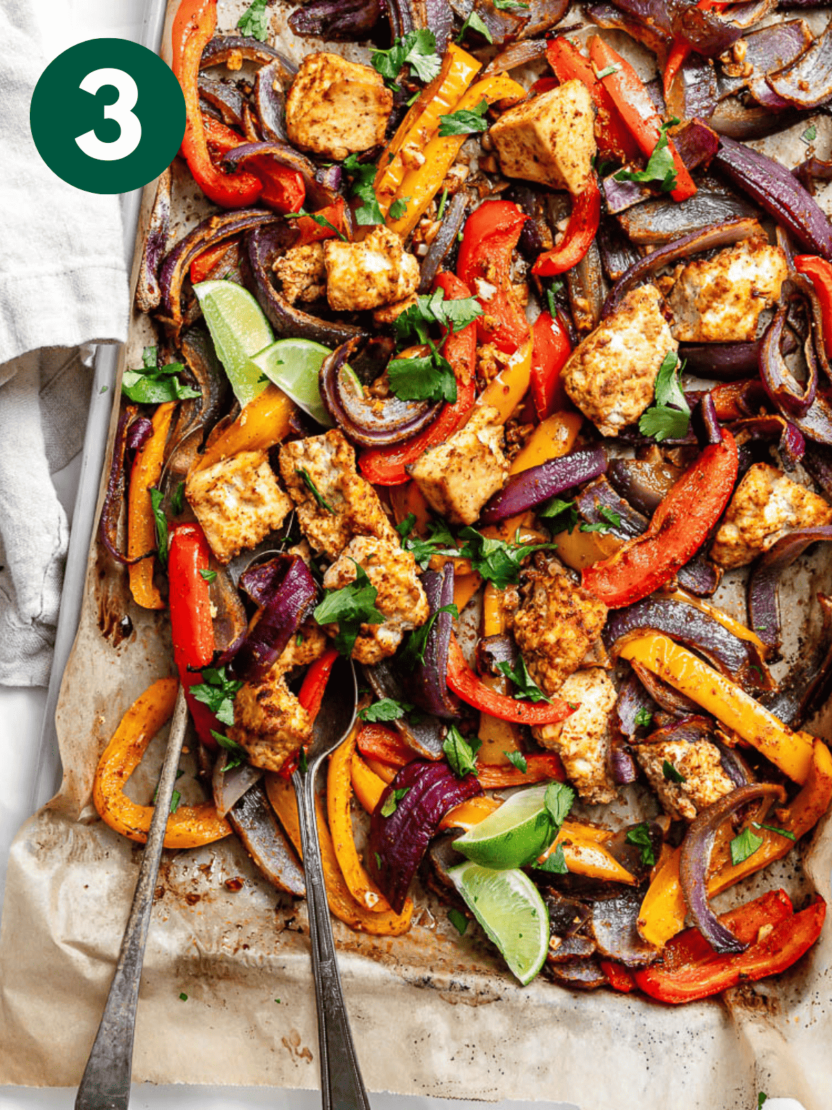 roasted taco-seasoned tofu c،ks, onion, and bell peppers on a parchment-lined sheet pan.