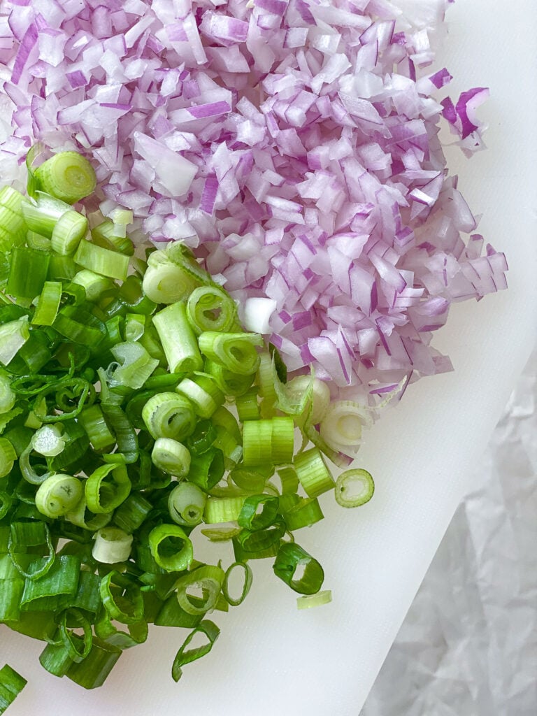 process shot showing diced green onions and onion on cutting board