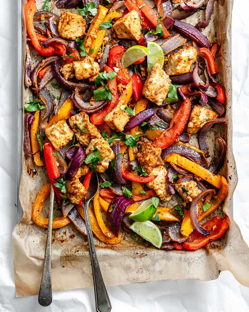 roasted taco-seasoned tofu chunks, onion, and bell peppers on a parchment-lined sheet pan.