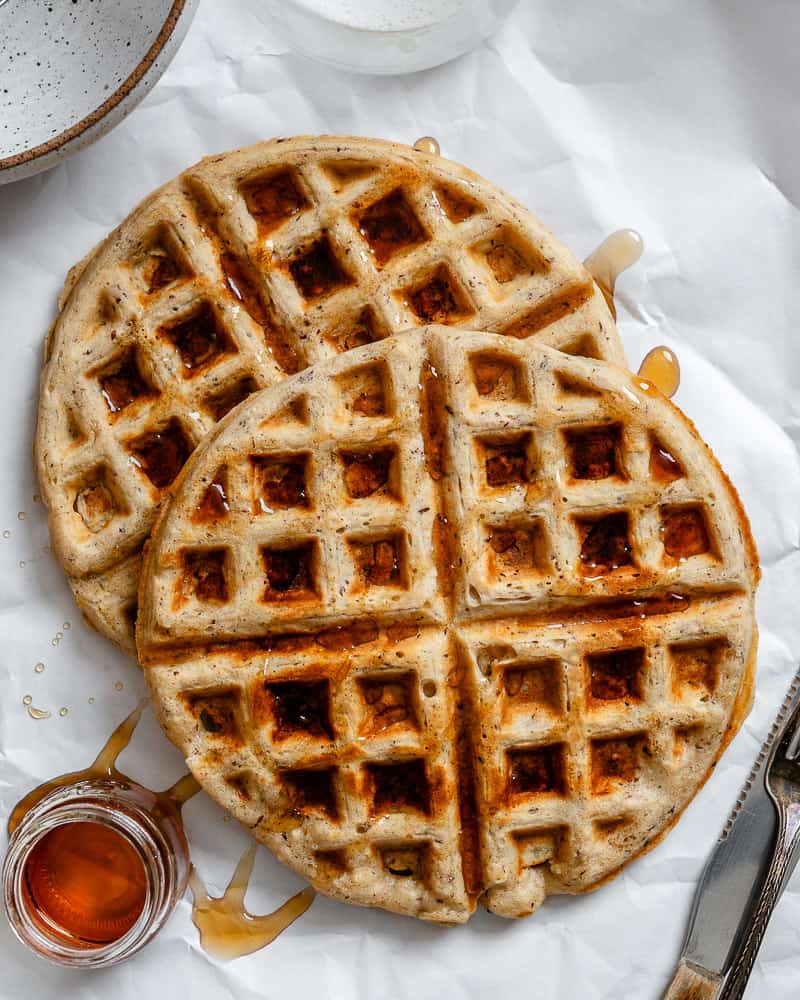 a stack of vegan waffles with maple syrup drizzled on top.