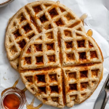 a stack of vegan waffles with maple syrup drizzled on top.