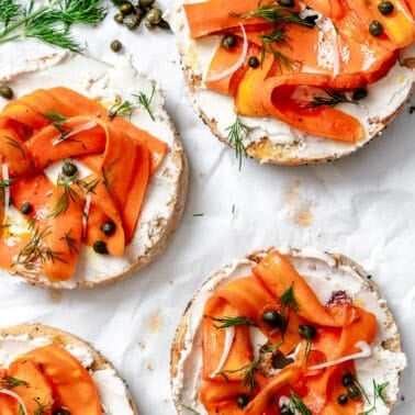 completed Carrot Lox [Vegan Smoked Salmon] spread out on bagel halves on a white surface