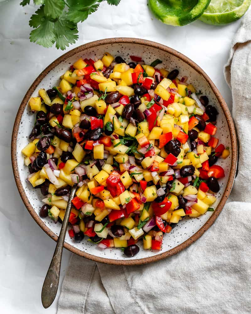 mango salsa and a metal spoon in a large white bowl.