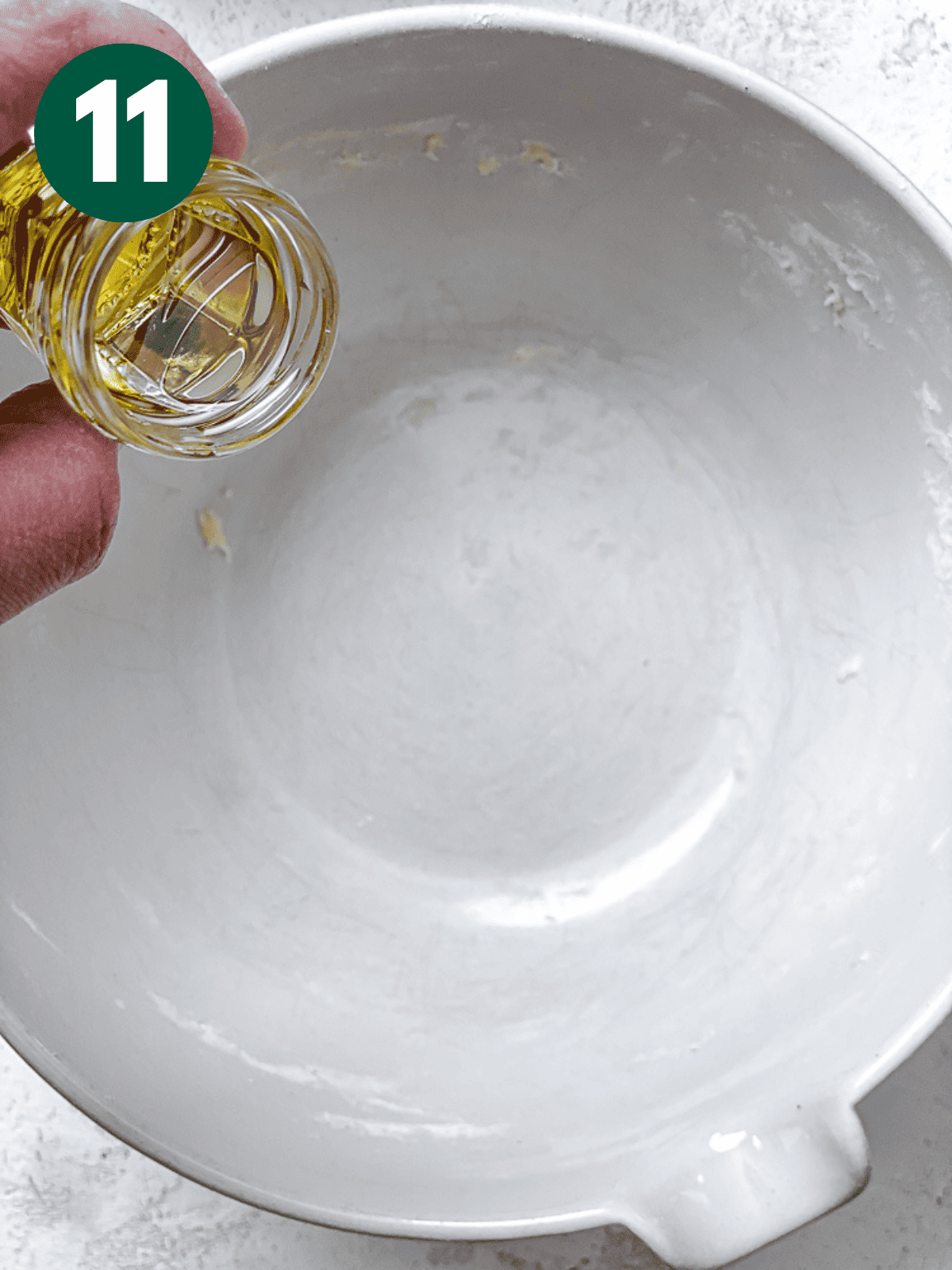 pouring oil into a large white bowl.