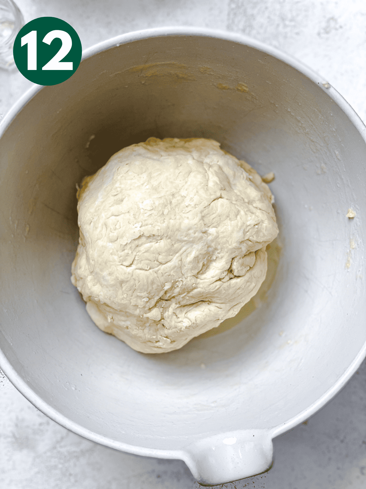 a ball of dough on top of oil in a large white bowl.