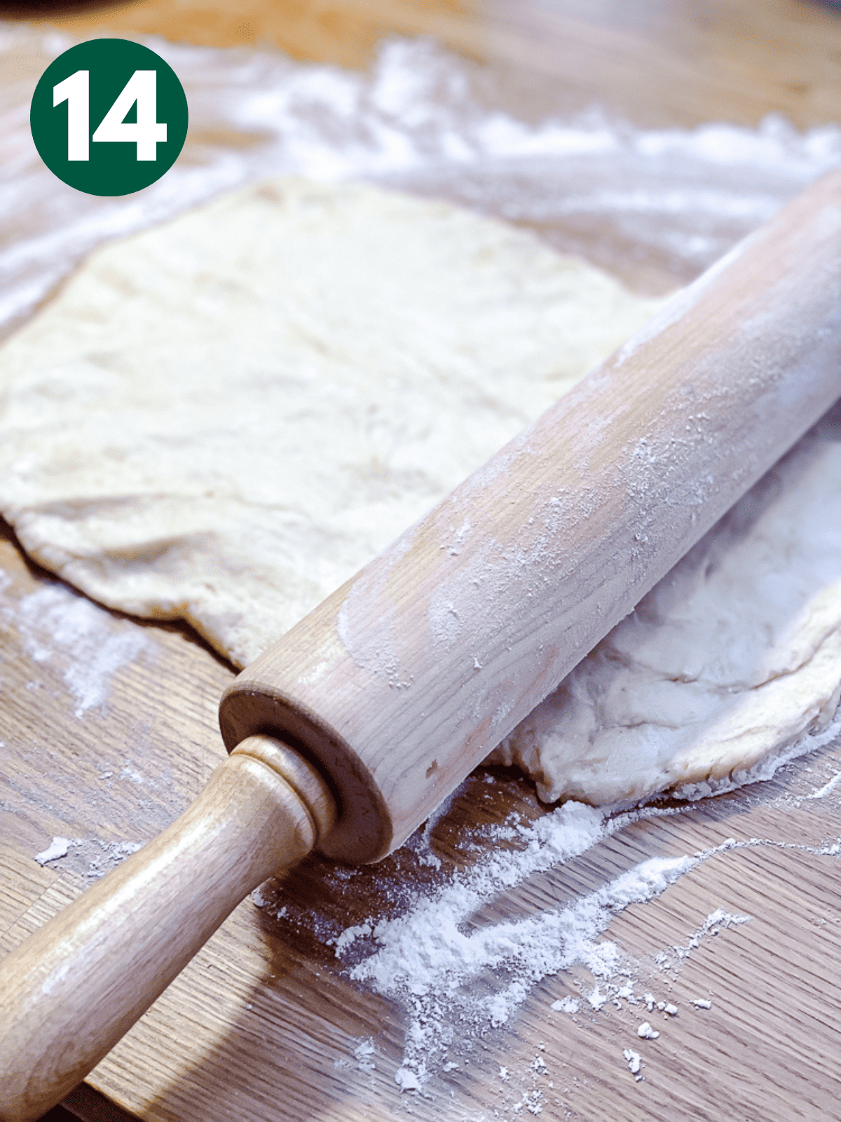 using a wooden rolling pin to roll out cinnamon roll dough.