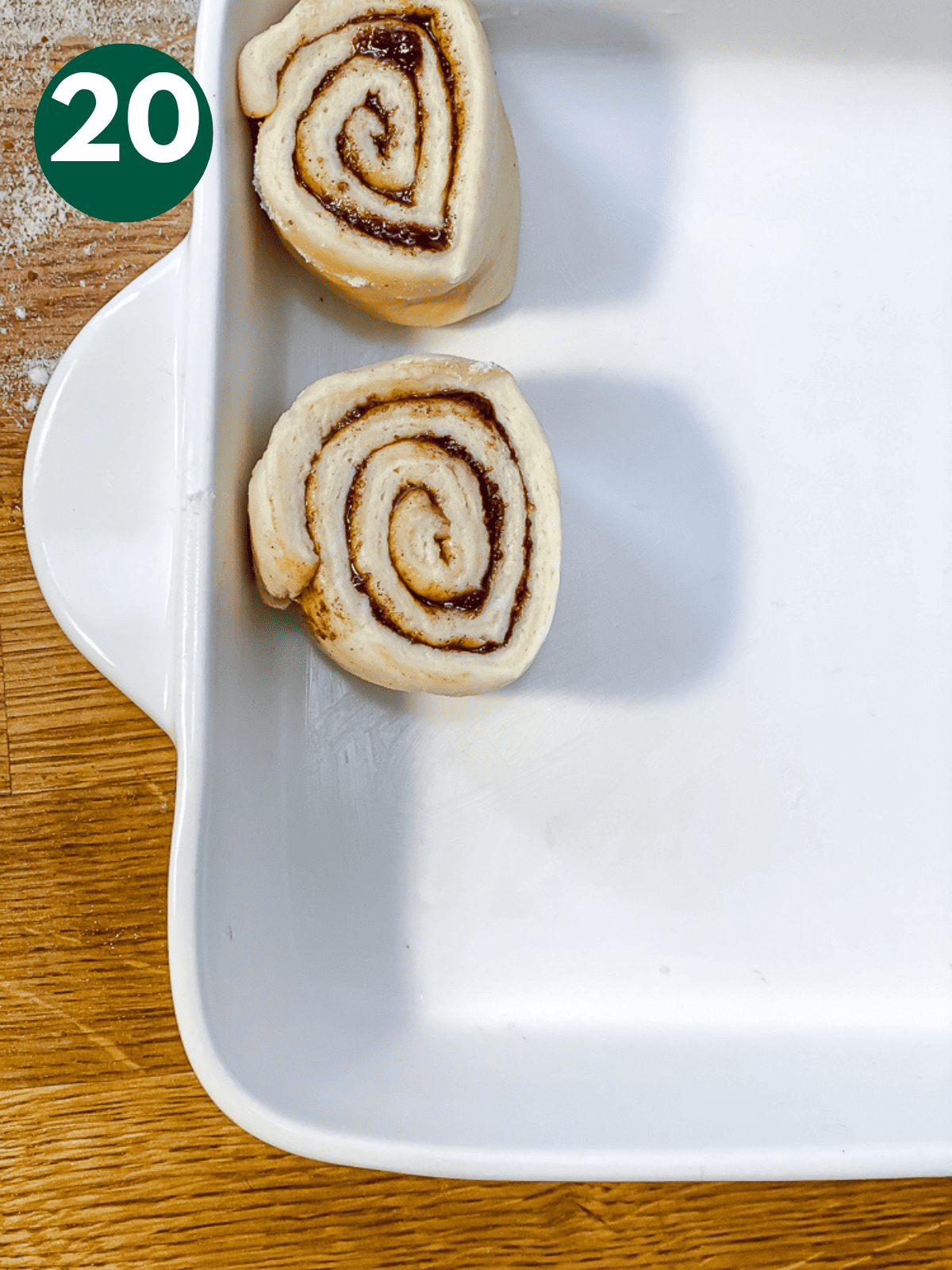 placing unbaked cinnamon rolls in a white baking dish.