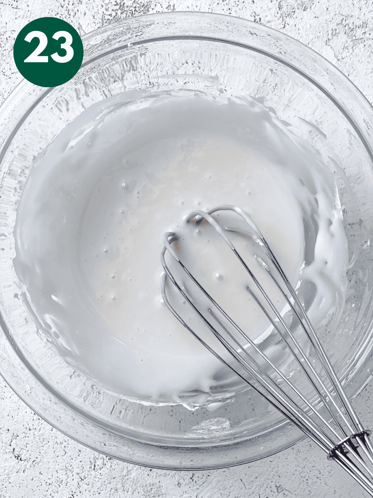 whisking vanilla icing in a large glass bowl.