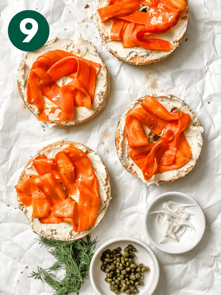 completed Carrot Lox [Vegan Smoked Salmon] spread out on bagel halves on a white surface