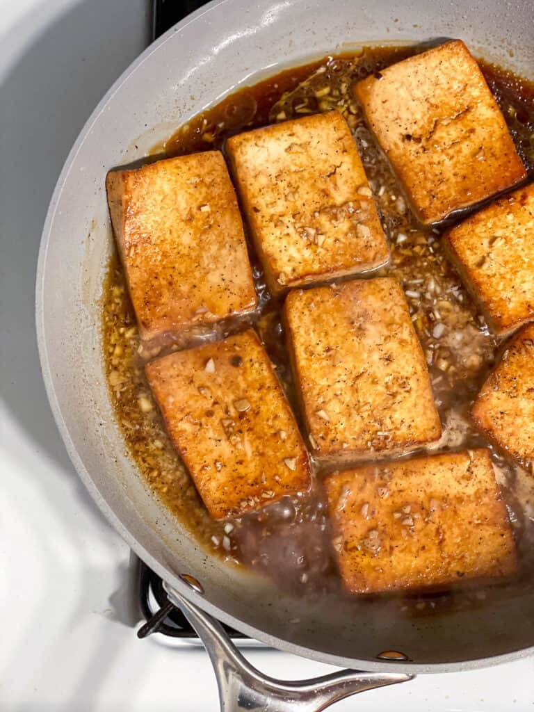 process shot showing tofu cooking with marinade on skillet