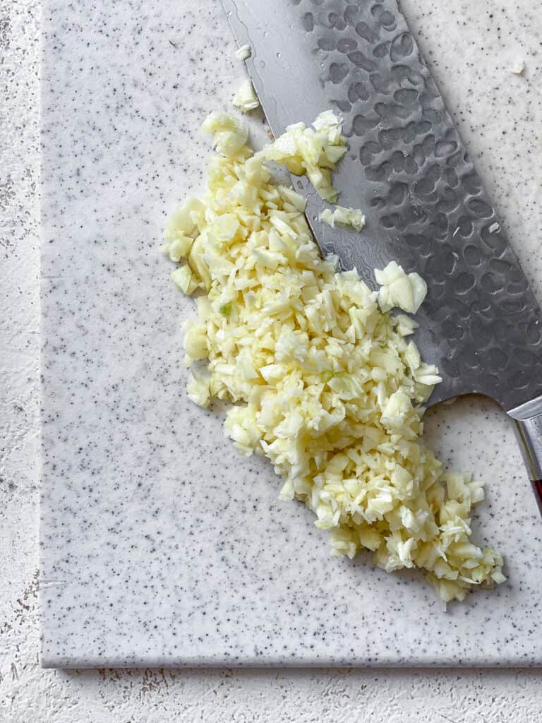 process s،t of slicing garlic on cutting board
