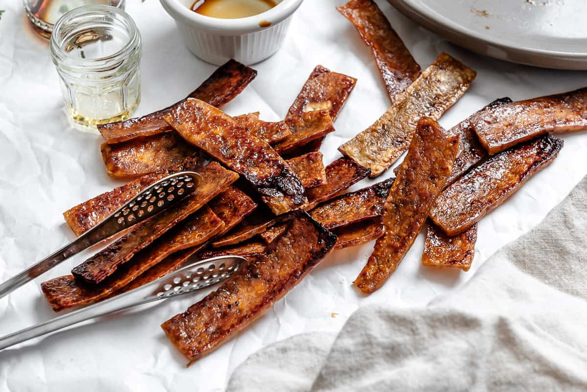 a pile of sauce-covered and baked vegan tofu bacon strips.