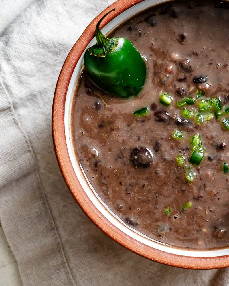 close up on black bean soup topped with diced jalapenos in a bowl.