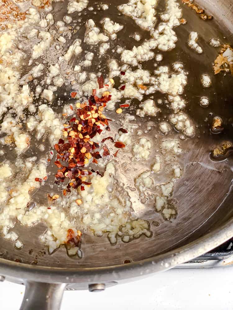 Minced ginger, garlic, and red pepper flakes cooking in the pan