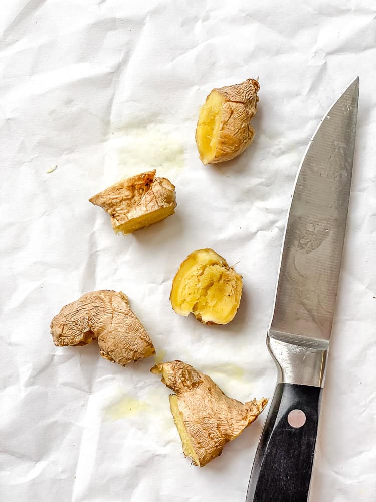 process shot of crushing ginger root on white surface