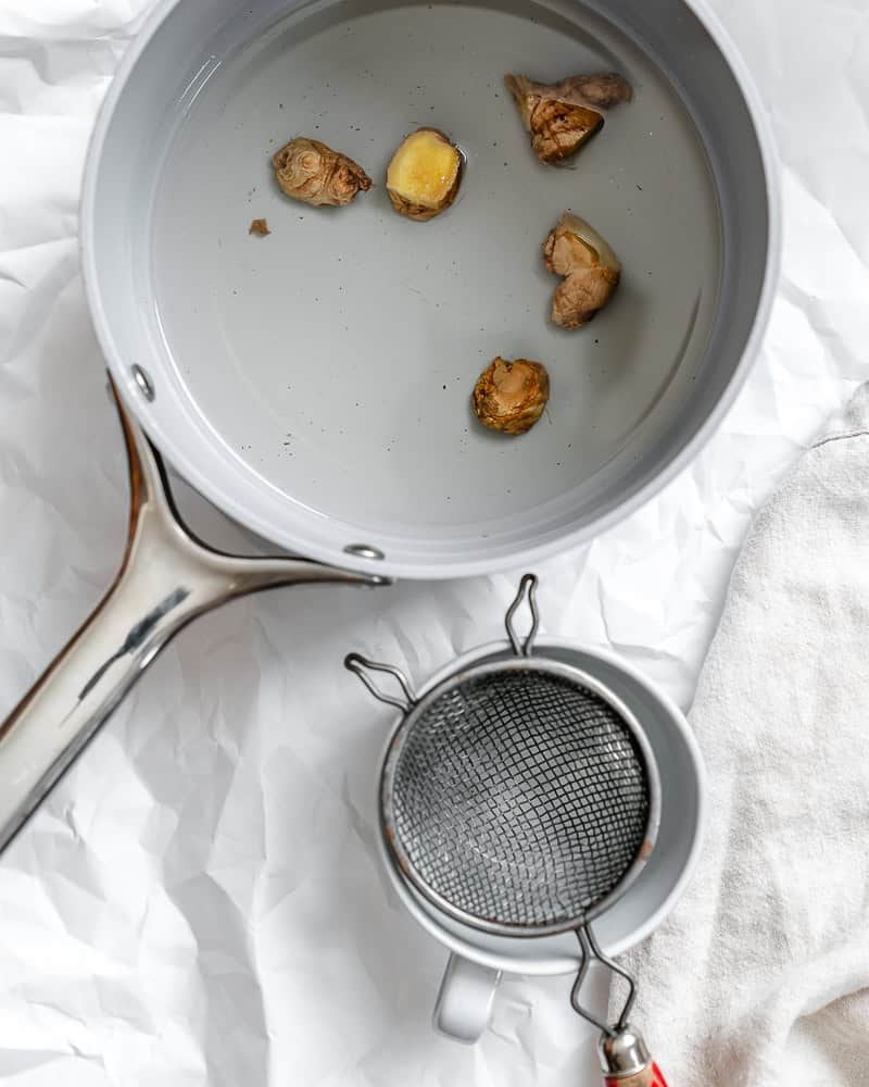 process shot showing ginger in pot alongside pitcher of water