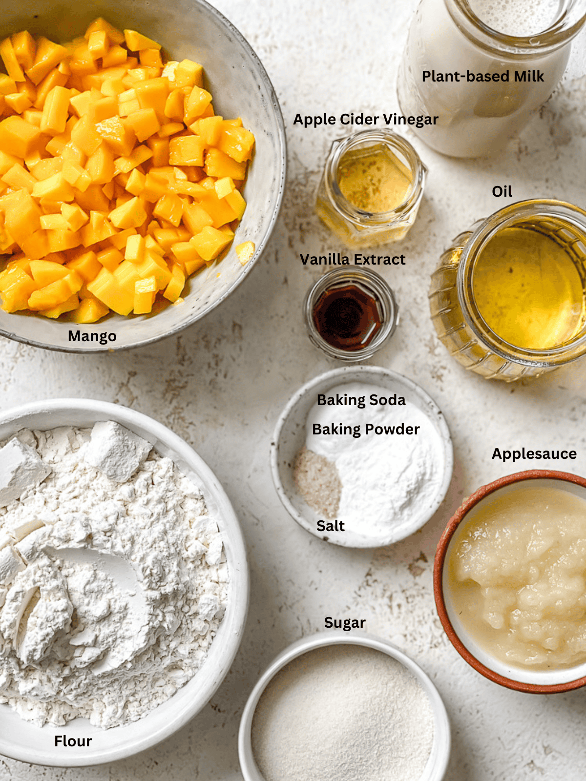 ingredients for mango cake in individual bowls with labels.