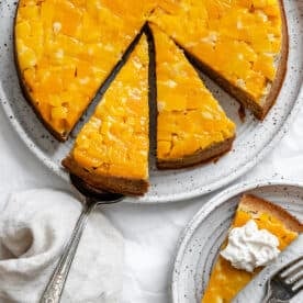 a sliced mango cake next to a slice of cake on a small white plate.