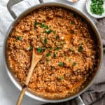 close up on a wooden spoon in a batch of cooked sofritas in a metal pan.
