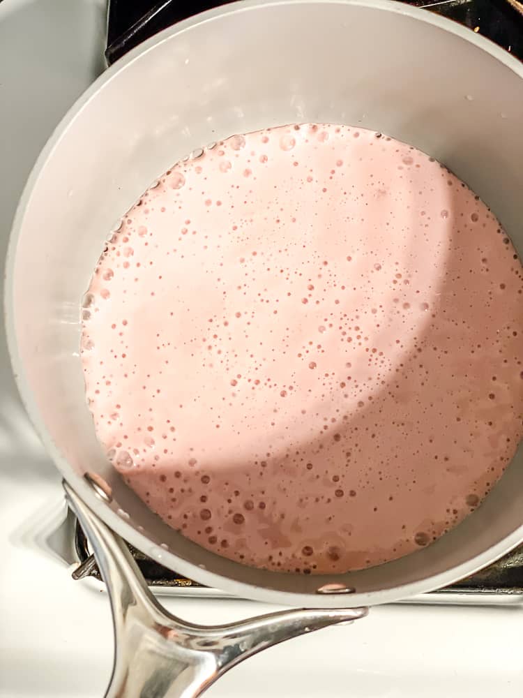 Process shot showing strawberry milk added to pot.
