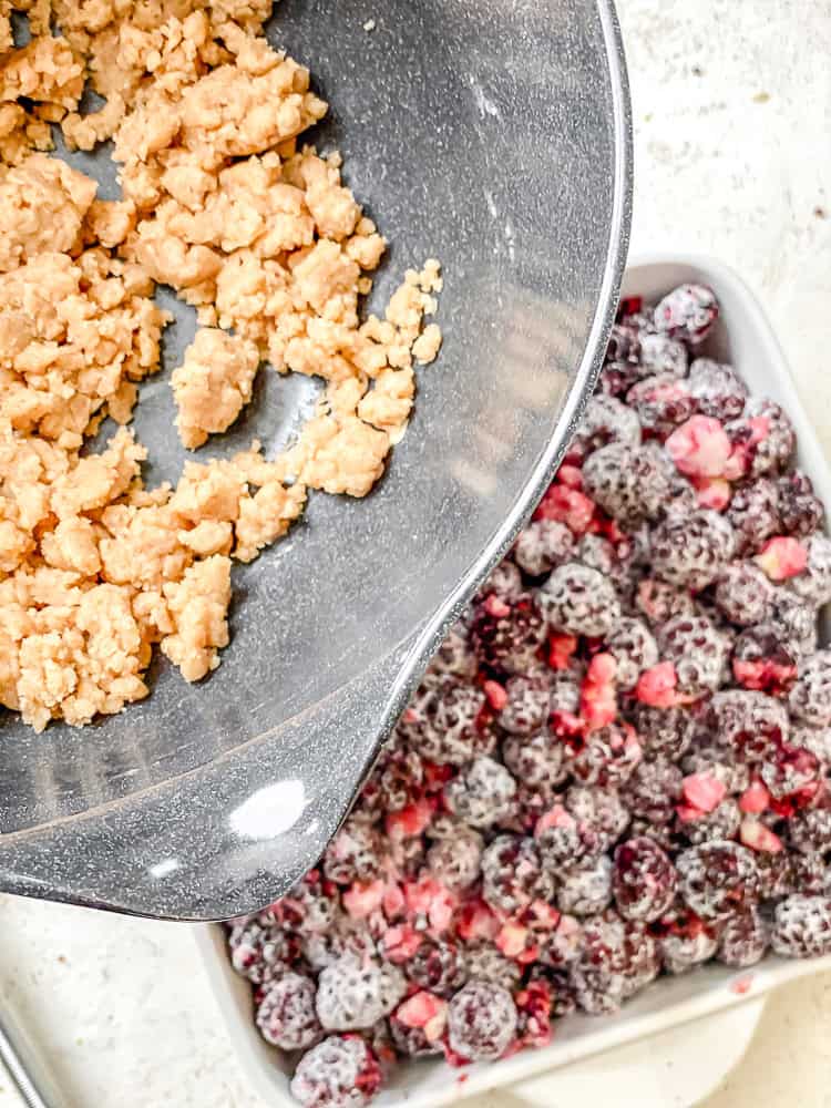Process shot showing adding crumble mixture to berries.