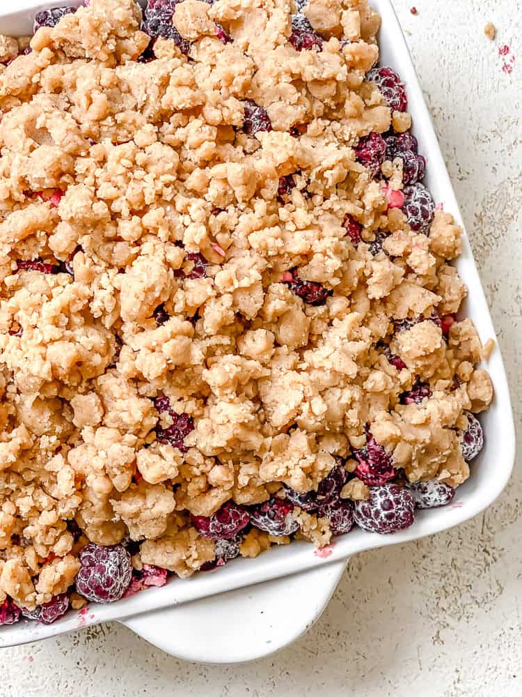Process shot showing pre-baked blackberry crumble in a baking pan.
