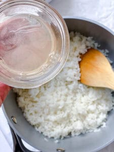 seasoning cooked sushi rice with a rice vinegar mixture.