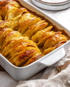 Close-up of baked vegan scalloped potatoes with golden edges in a white casserole dish.