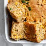 close up on slices of baked jalapeno cornbread in a white baking dish.