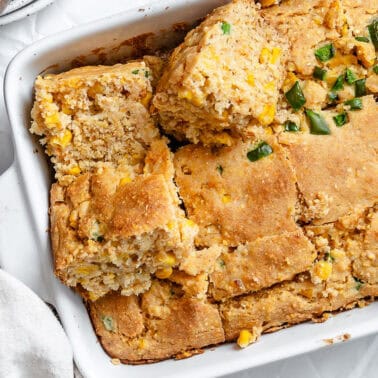 slices of baked jalapeno cornbread in a white baking dish.