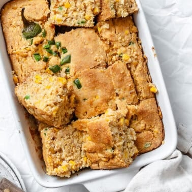 slices of baked jalapeno cornbread in a white baking dish.