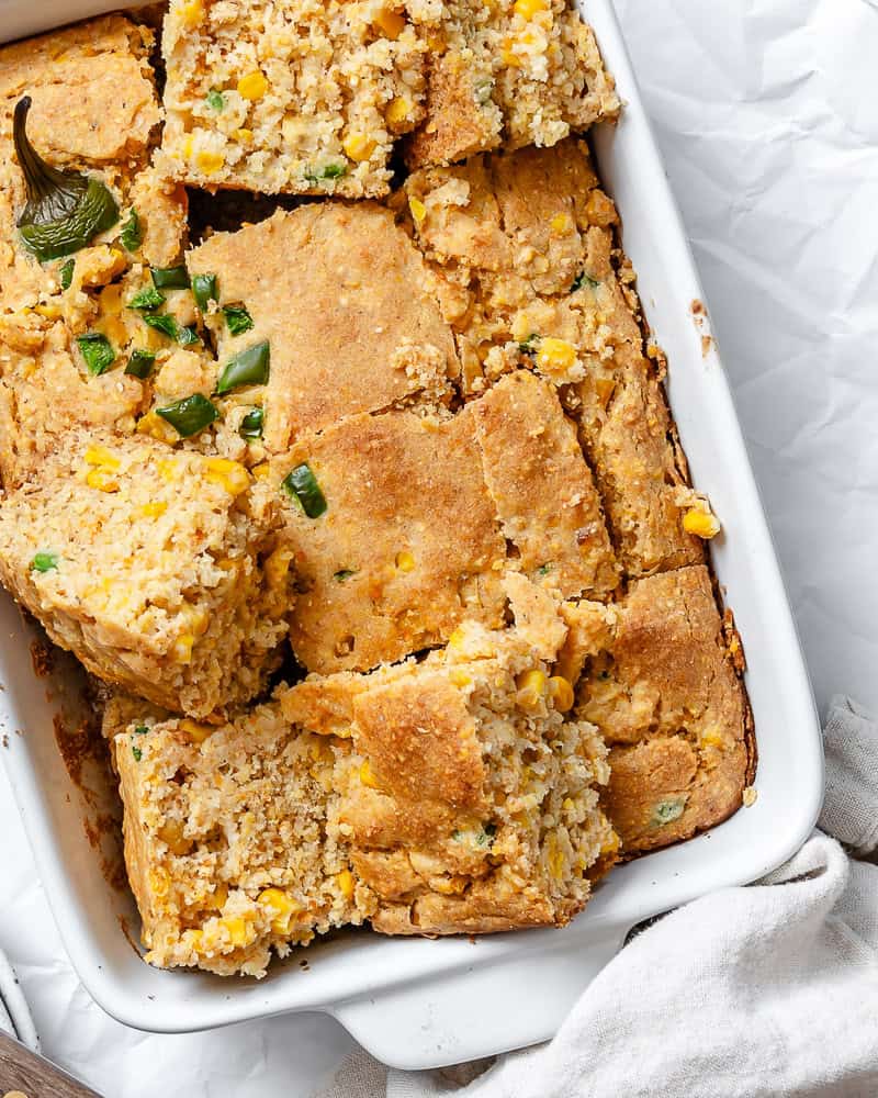 slices of baked jalapeno cornbread in a white baking dish.