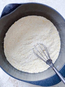 whisking the dry ingredients for Vegan Jalapeño Cornbread in a large bowl.