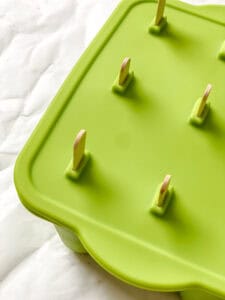 Frozen lemon popsicles in green molds.