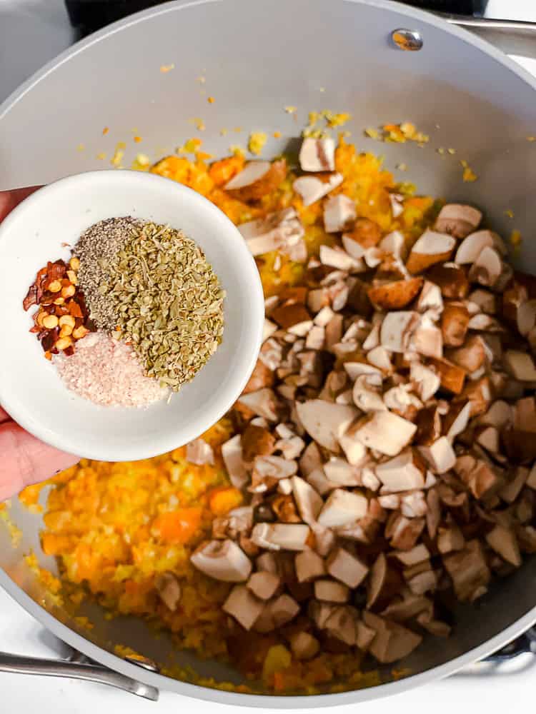 a bowl of spices above a pot of cooked veggies.