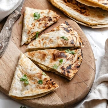 a vegan bean quesadilla sliced into fours on a wooden board.