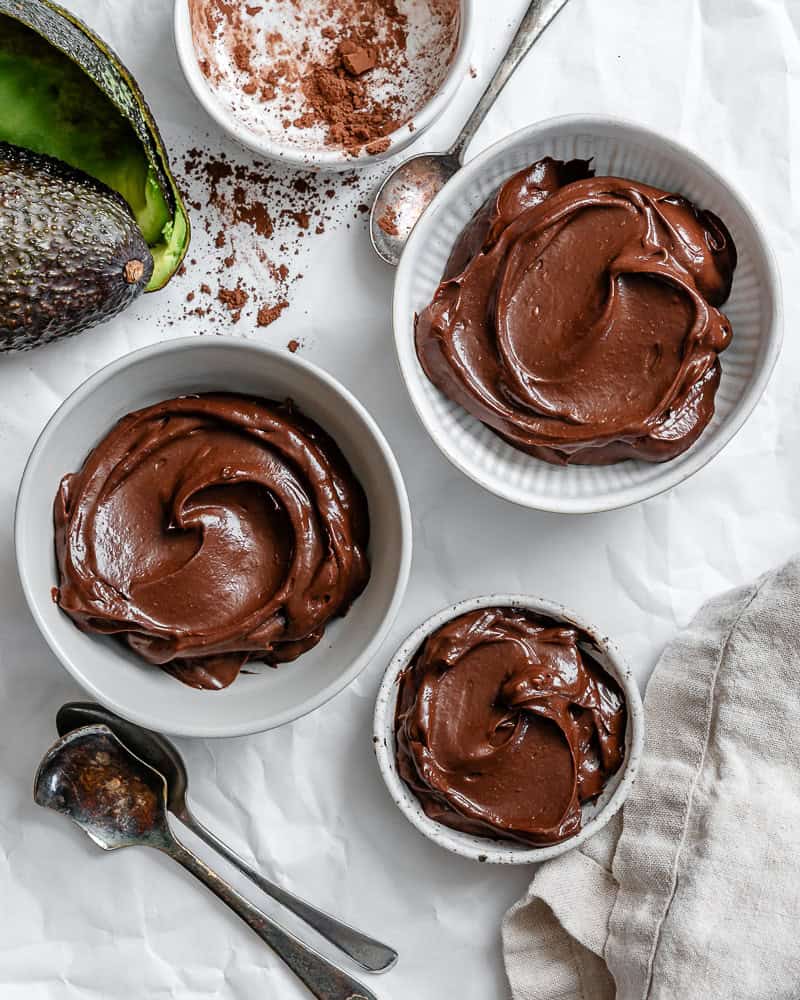 3 white bowls of chocolate avocado mousse.
