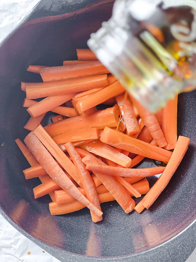 process shot showing olive oil being poured onto carrots